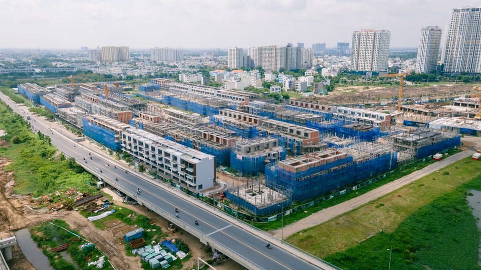 Dãy nhà phố thương mại Senturia An Phú bám đường Song Hành đang tô mặt ngoài, lưới bao che xanh và cần cẩu phía sau, tháng 6/2026
