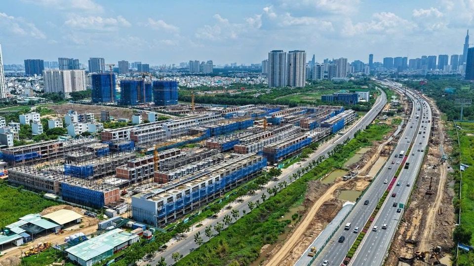 Ảnh flycam công trường Senturia An Phú tháng 6/2026: các dãy nhà phố đã cất nóc chạy dọc cao tốc Long Thành, phía xa là các toà cao tầng khu An Phú