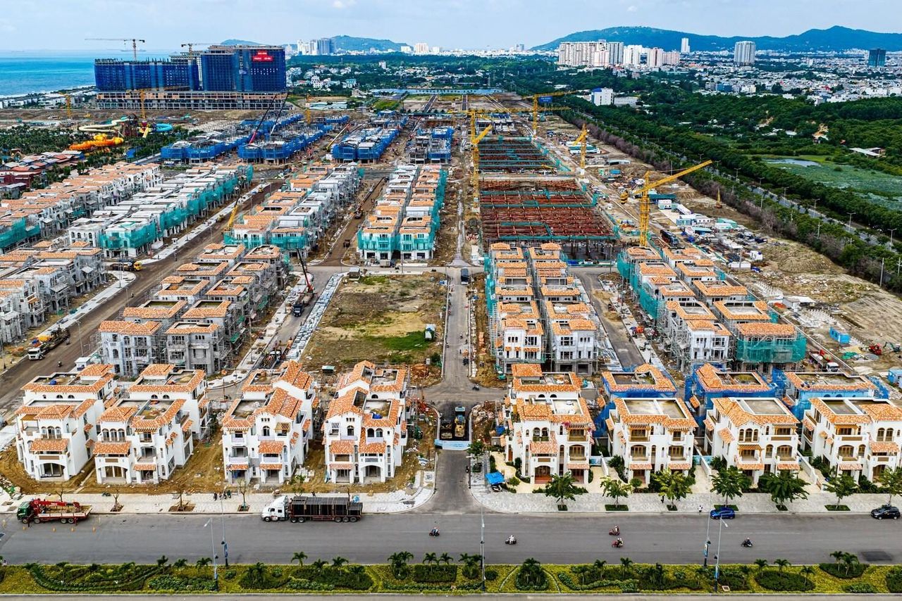 Ảnh chụp từ trên cao tháng 9/2026: các dãy nhà phố Casa Townhouse ở Blanca City đã lên mái, tường trắng mái ngói đỏ, phía xa là tháp cao tầng đang xây