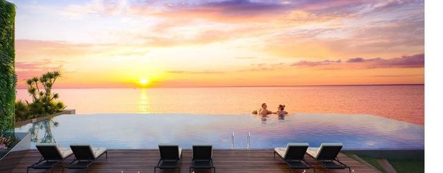 Phối cảnh hồ bơi Skyview trên sân thượng Five Star Odyssey: hồ bơi tràn bờ nhìn ra mặt biển lúc hoàng hôn, ghế nằm trên sàn gỗ